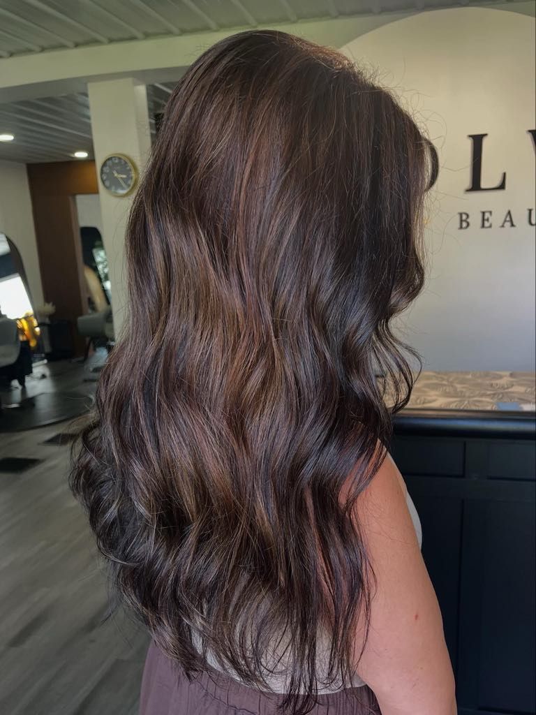 Woman with long wavy brown hair at a salon, the 