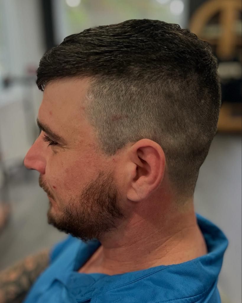 Man with a faded haircut, dark hair on top, and a beard, wearing a blue top.