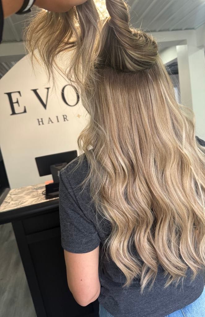 Woman with long, wavy, highlighted hair, styled at 