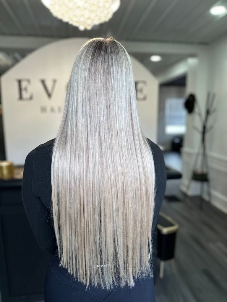 Woman with long, straight, light gray hair, standing in front of an 