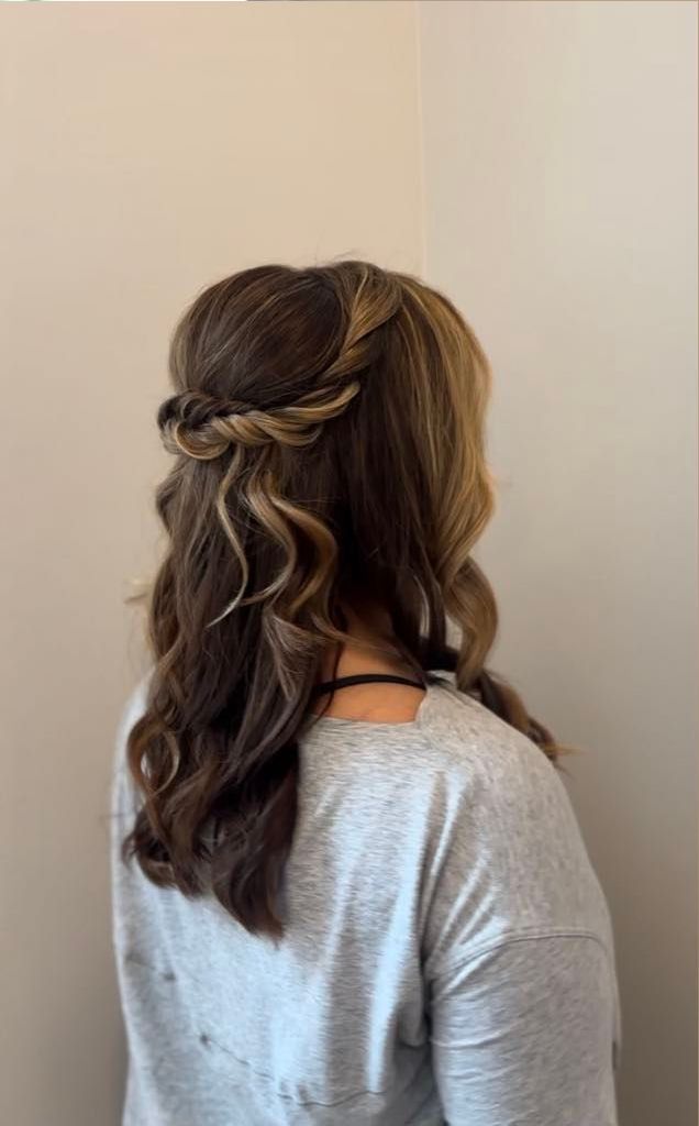 Woman with wavy, brown and blonde hair in a half-up twisted hairstyle, wearing a gray sweater.