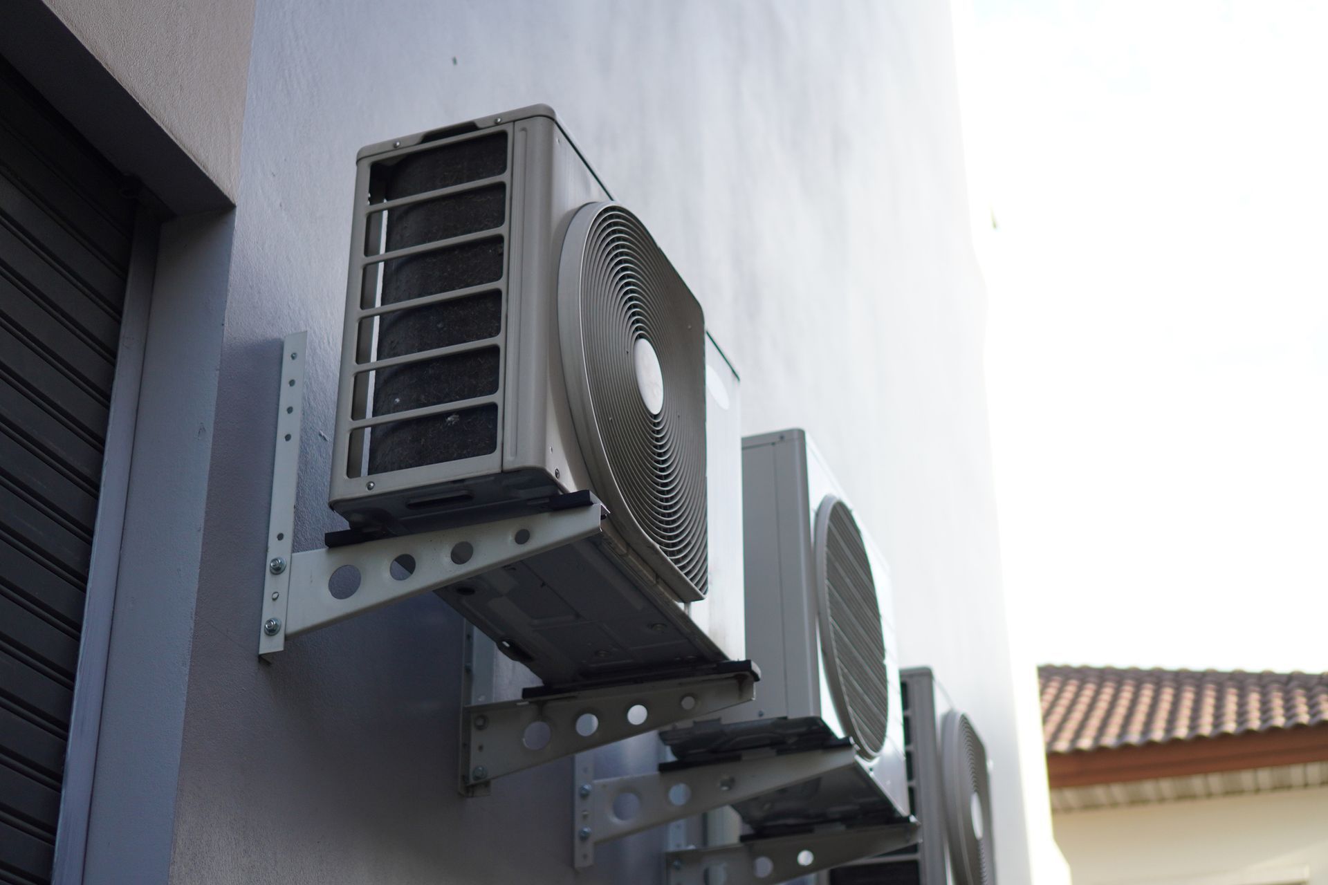 Wall-mounted air conditioning units, white, on a light gray exterior wall.