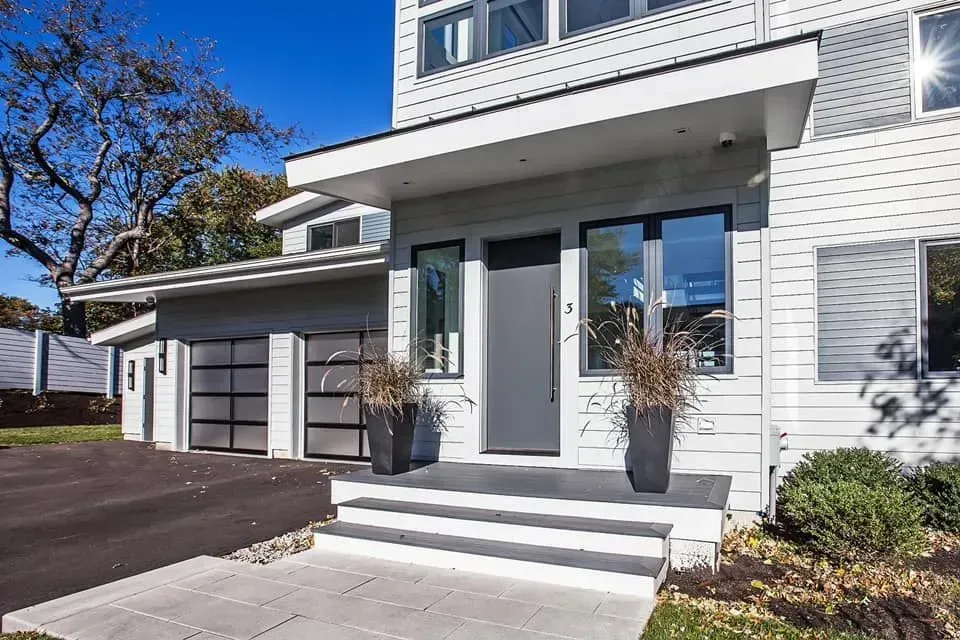 The front of a white house with a black garage door.