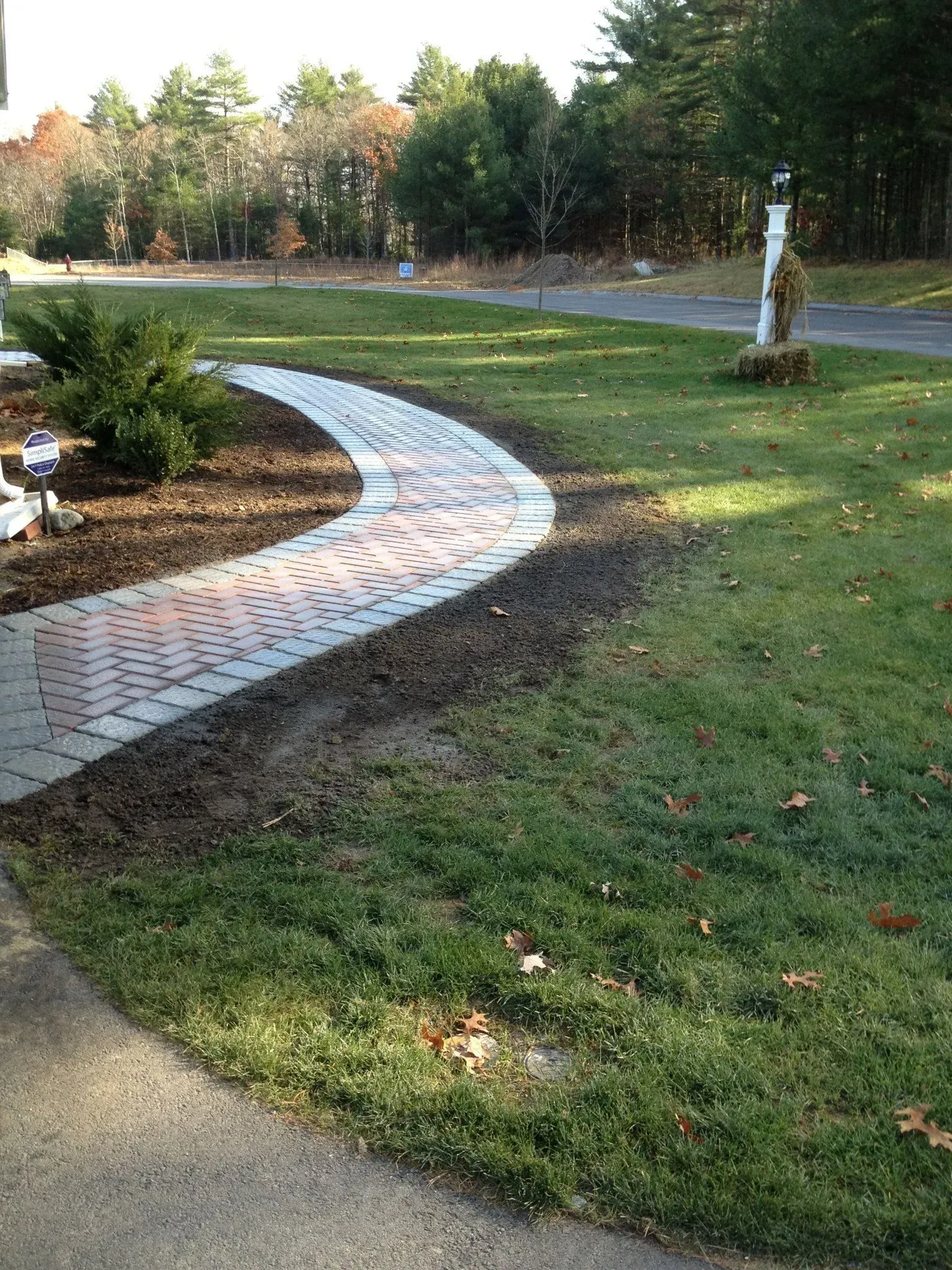 A brick walkway is going through a lush green field.