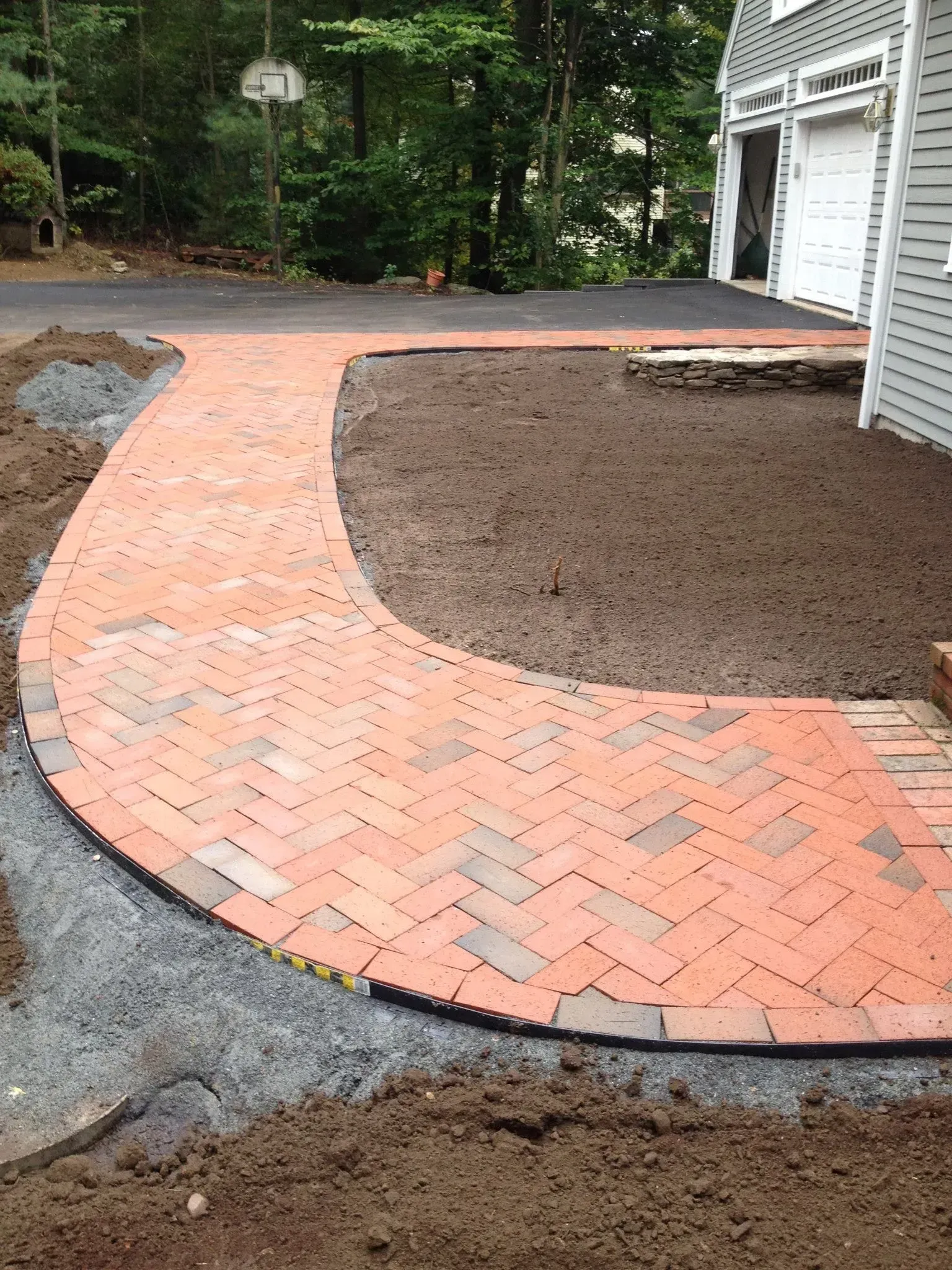 A brick walkway is being built in front of a garage.