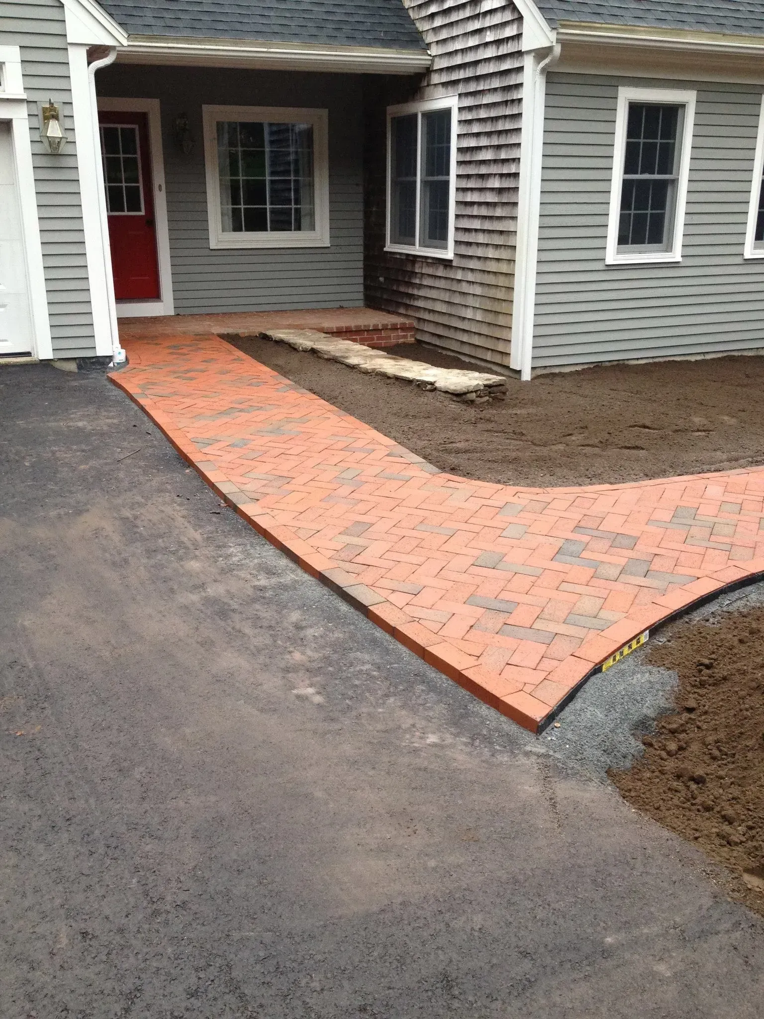 A brick walkway is being built in front of a house.