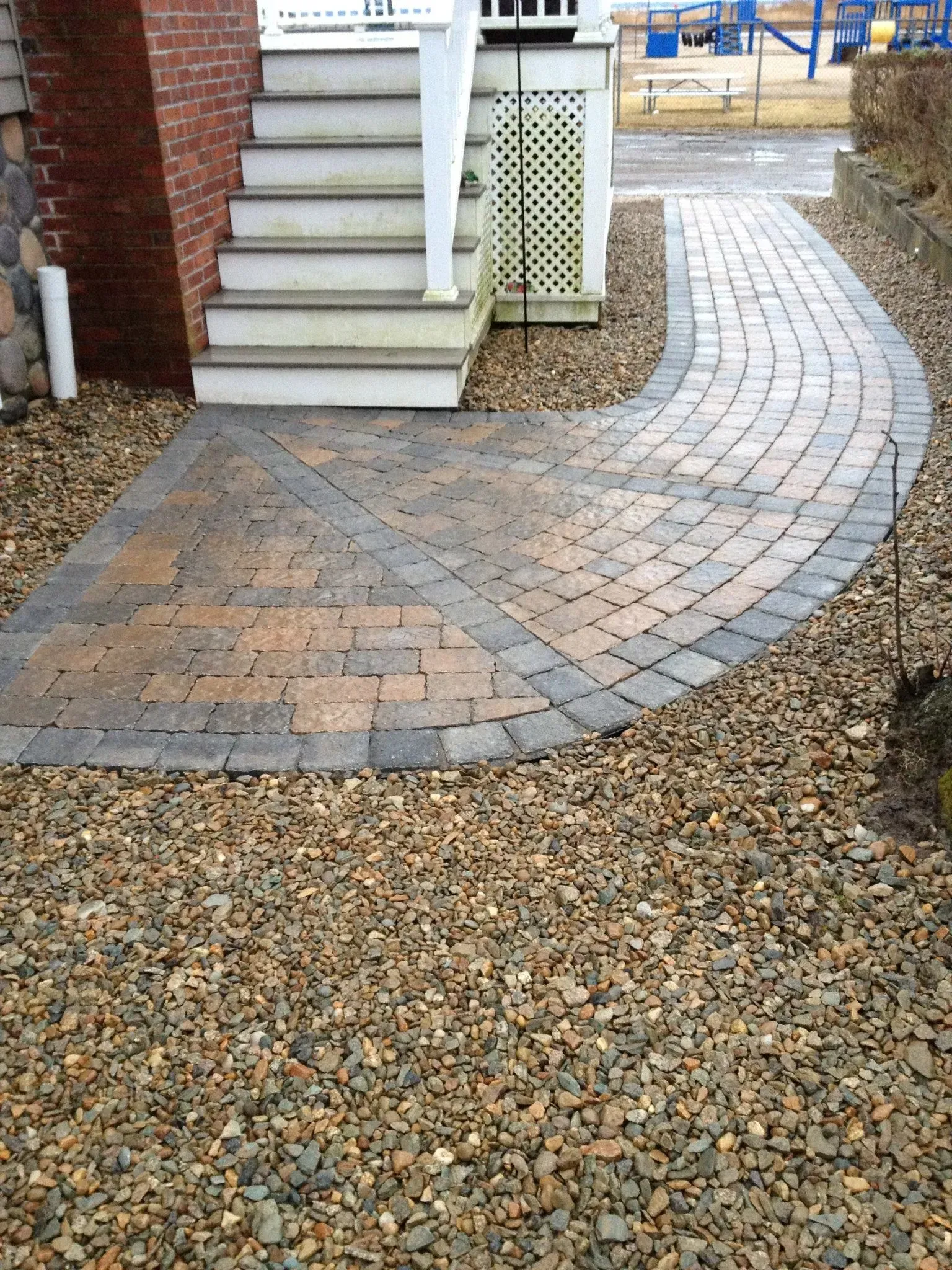 A brick walkway leading to a house with stairs
