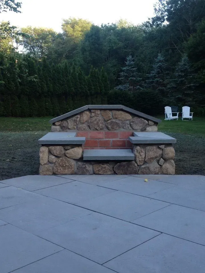 A brick fire pit sits in the middle of a patio