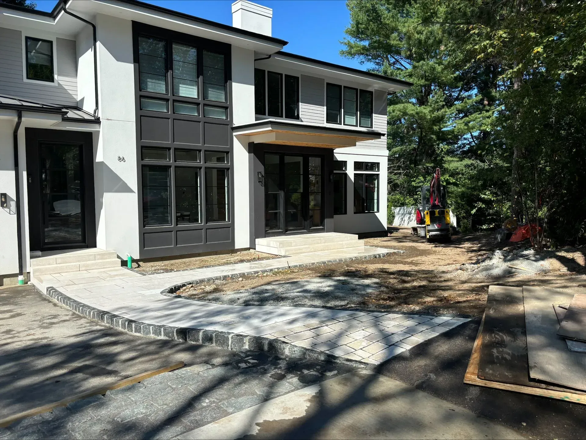 A large white house with black windows is being built.