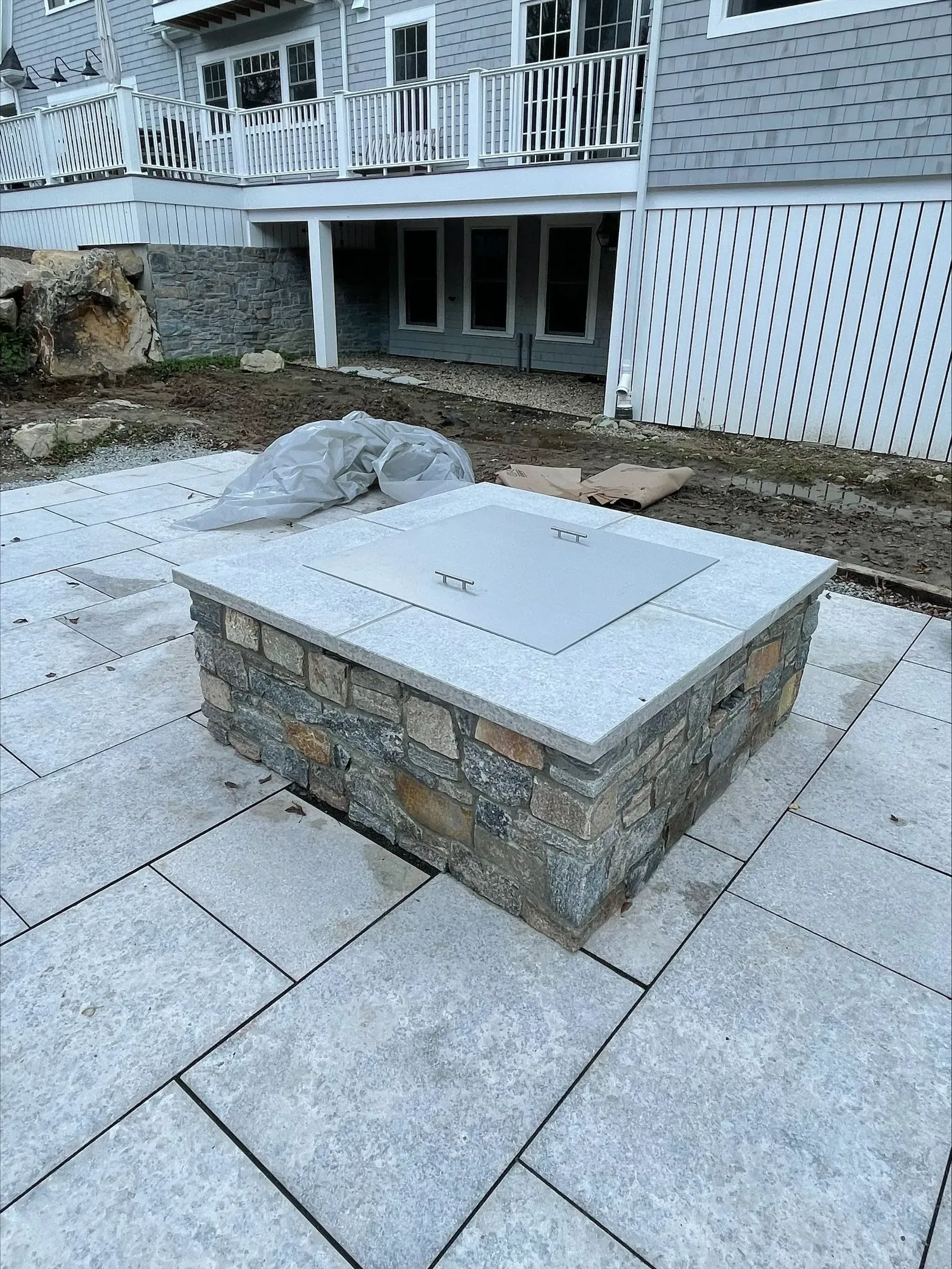 A fire pit is sitting on a patio in front of a house.
