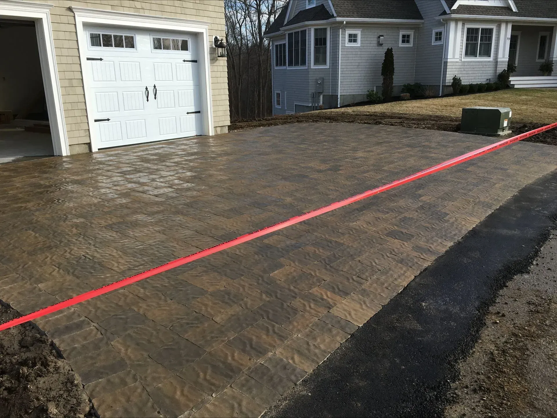 A red line is being measured on a driveway in front of a house.
