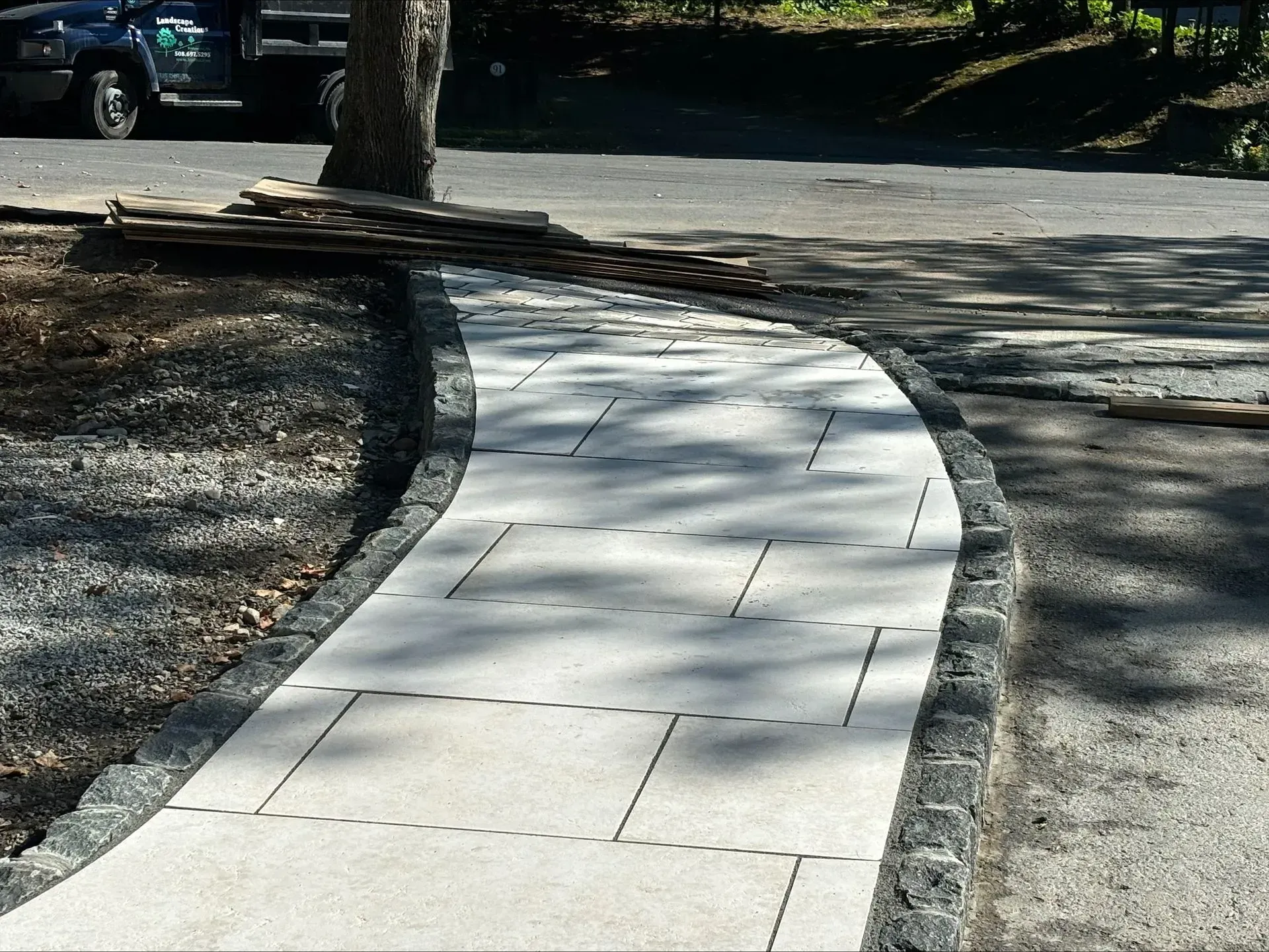 A sidewalk with a tree on the side of it