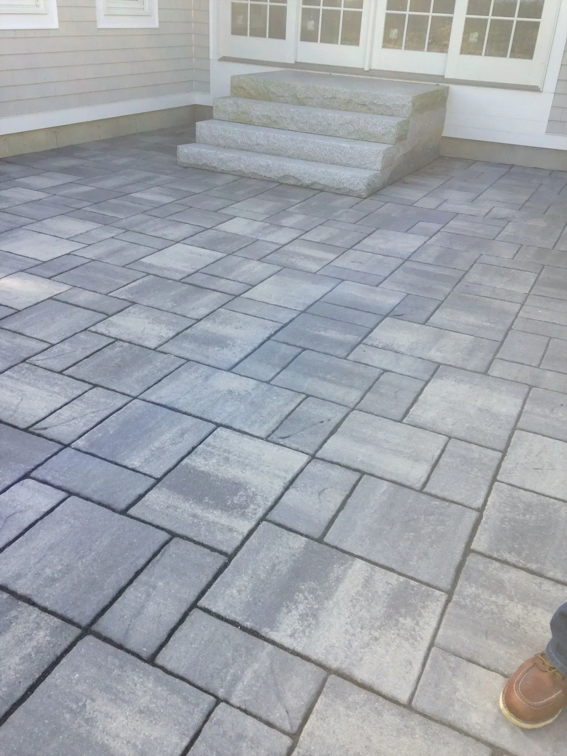 A person is standing on a brick patio next to stairs.