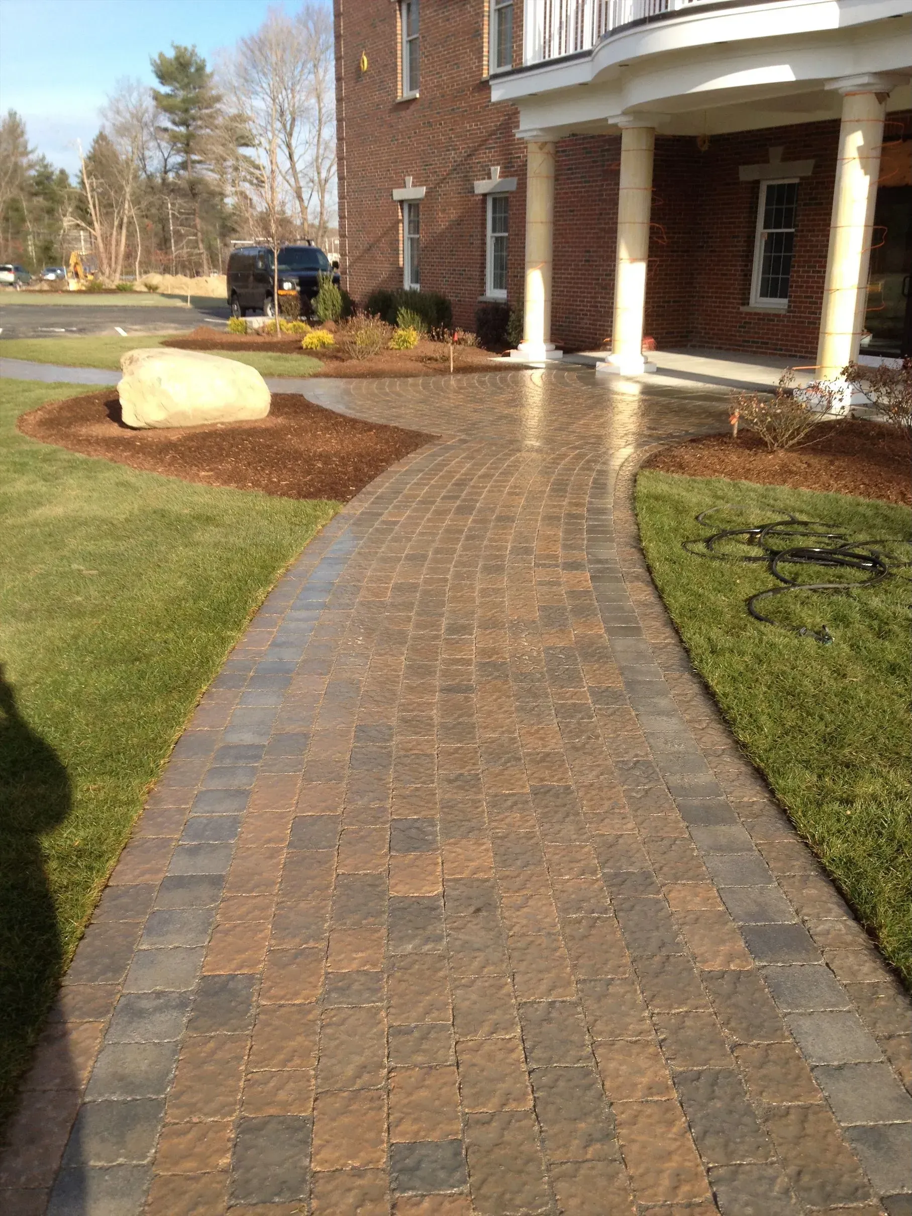 A brick walkway leading to a large brick house.