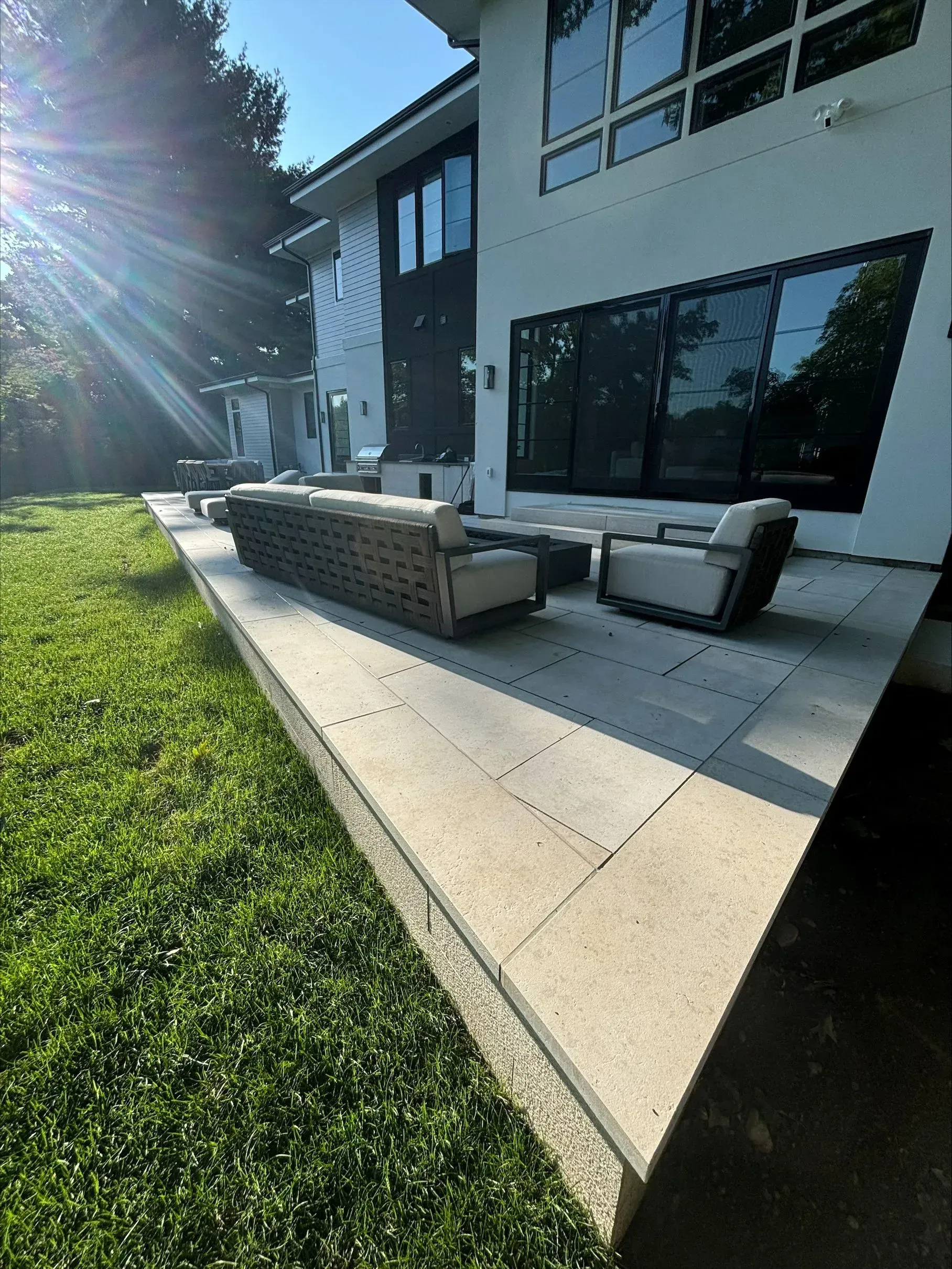 A patio with a couch and chairs in front of a large house.