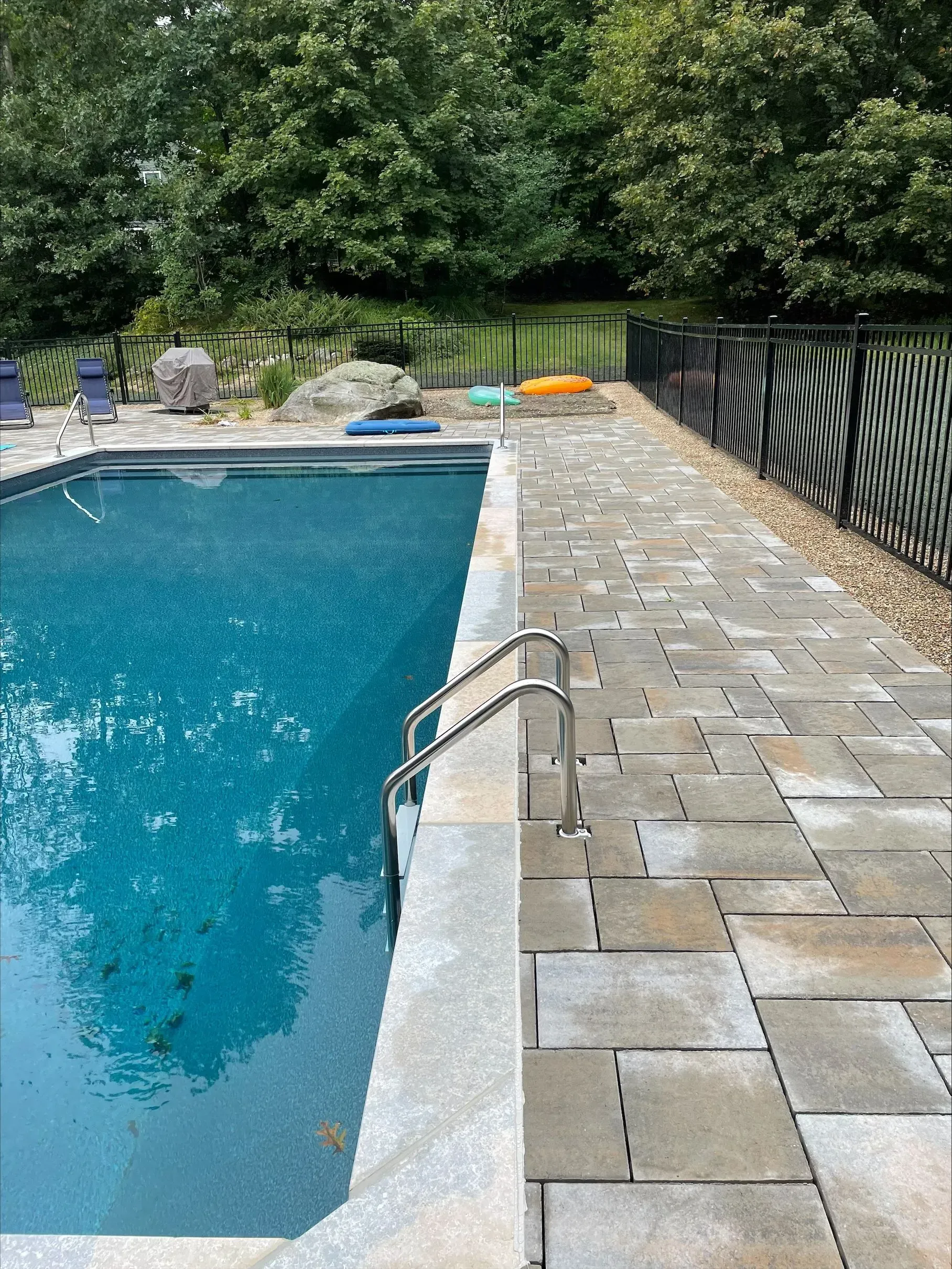 A large swimming pool with a brick walkway surrounding it.