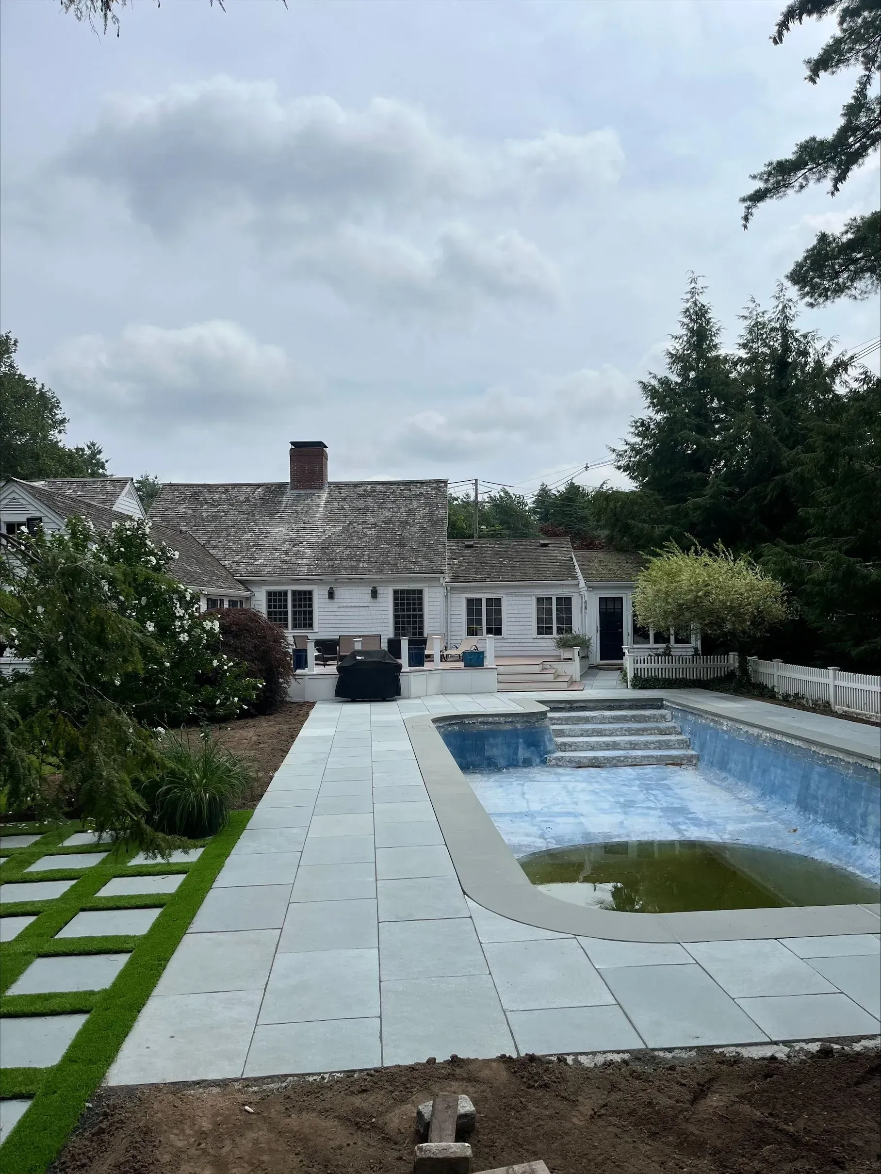 A large swimming pool is in the backyard of a house.