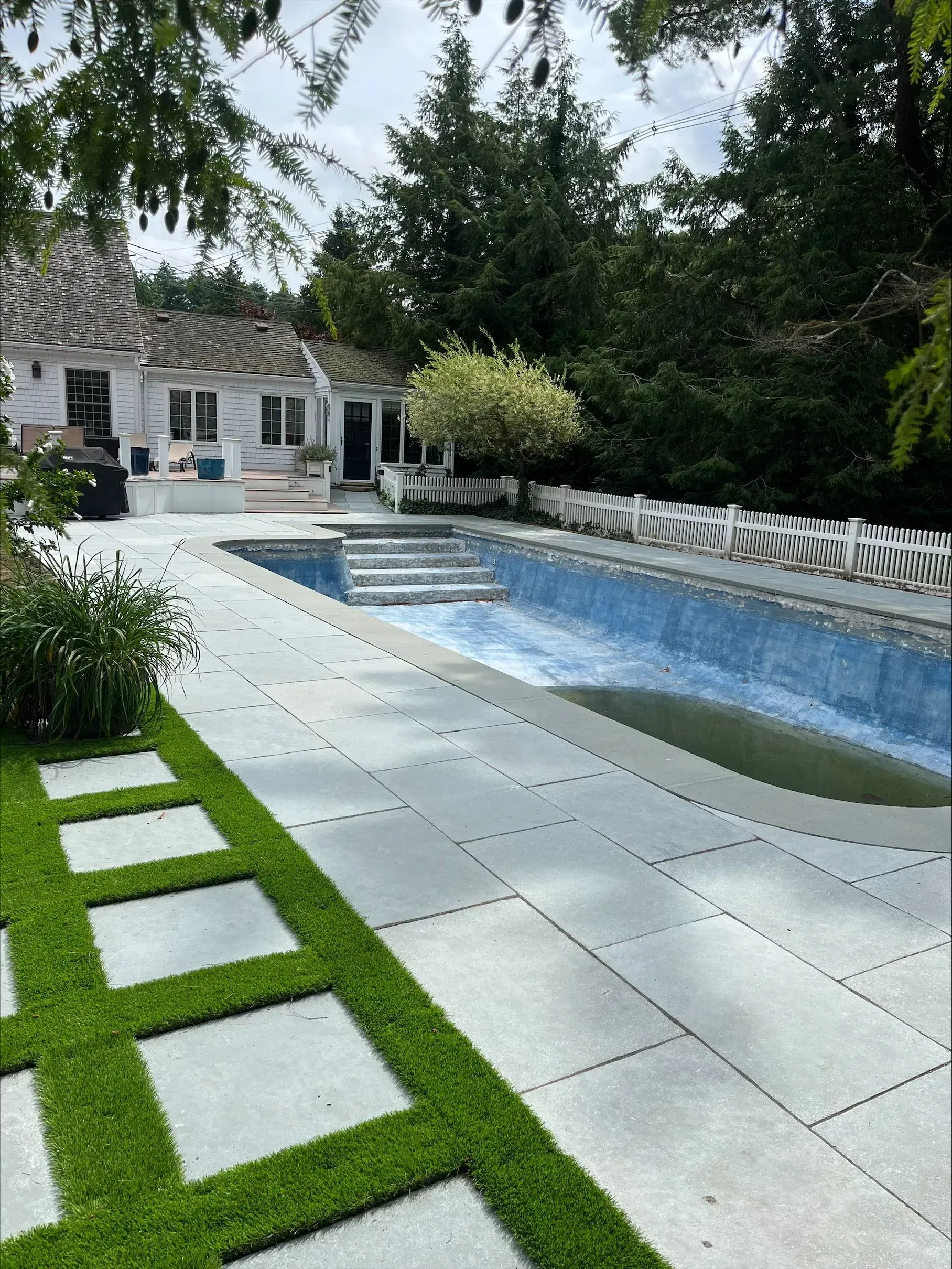 There is a large swimming pool in the backyard of a house.