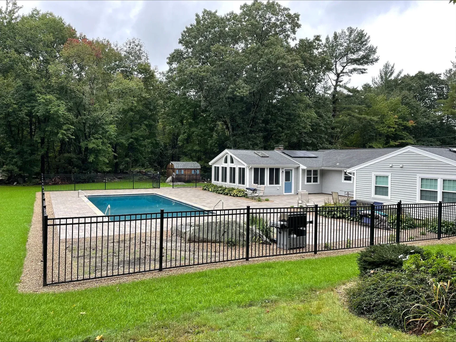 A house with a fence around it and a swimming pool in the backyard.
