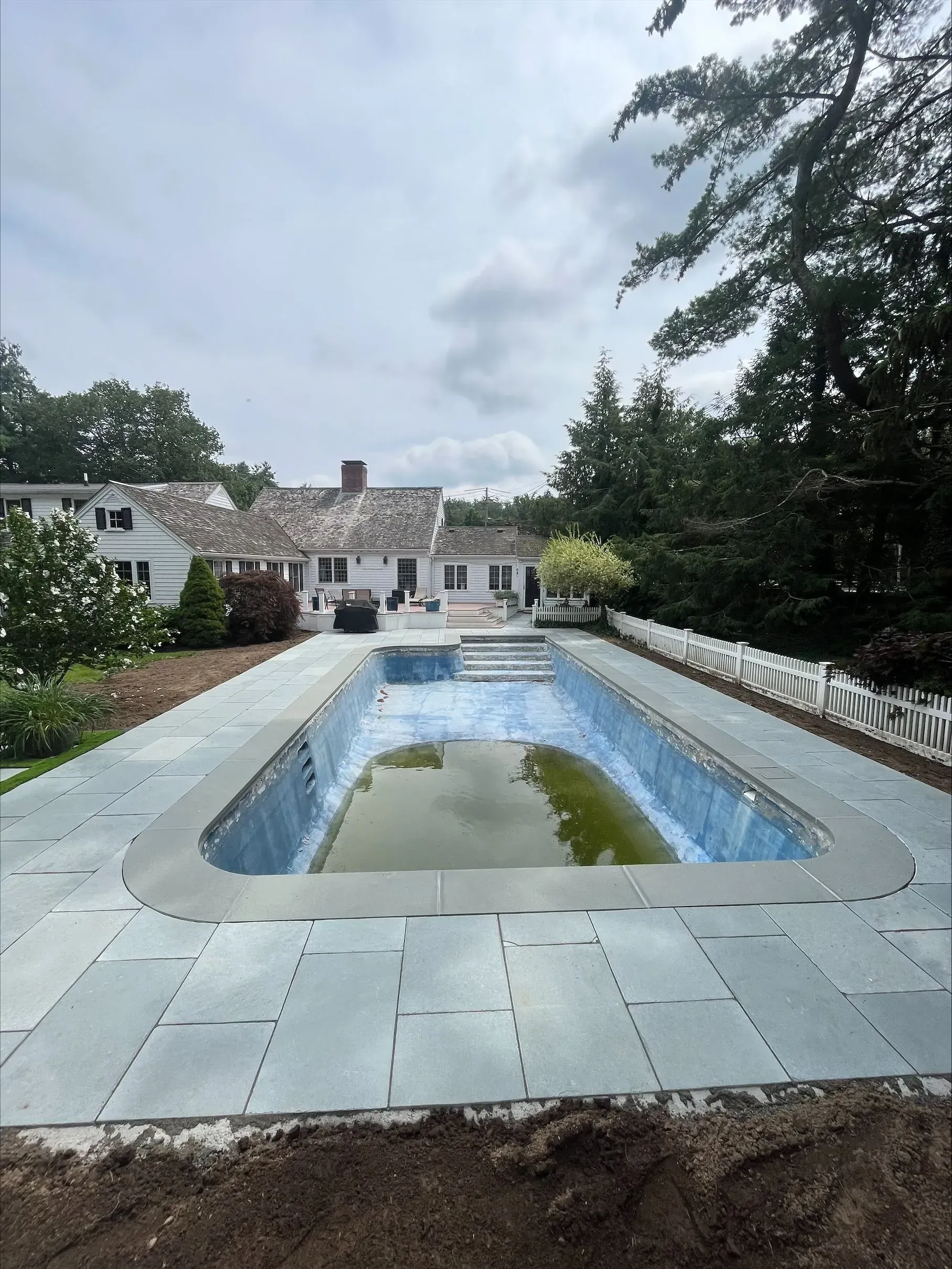 A large swimming pool with a house in the background