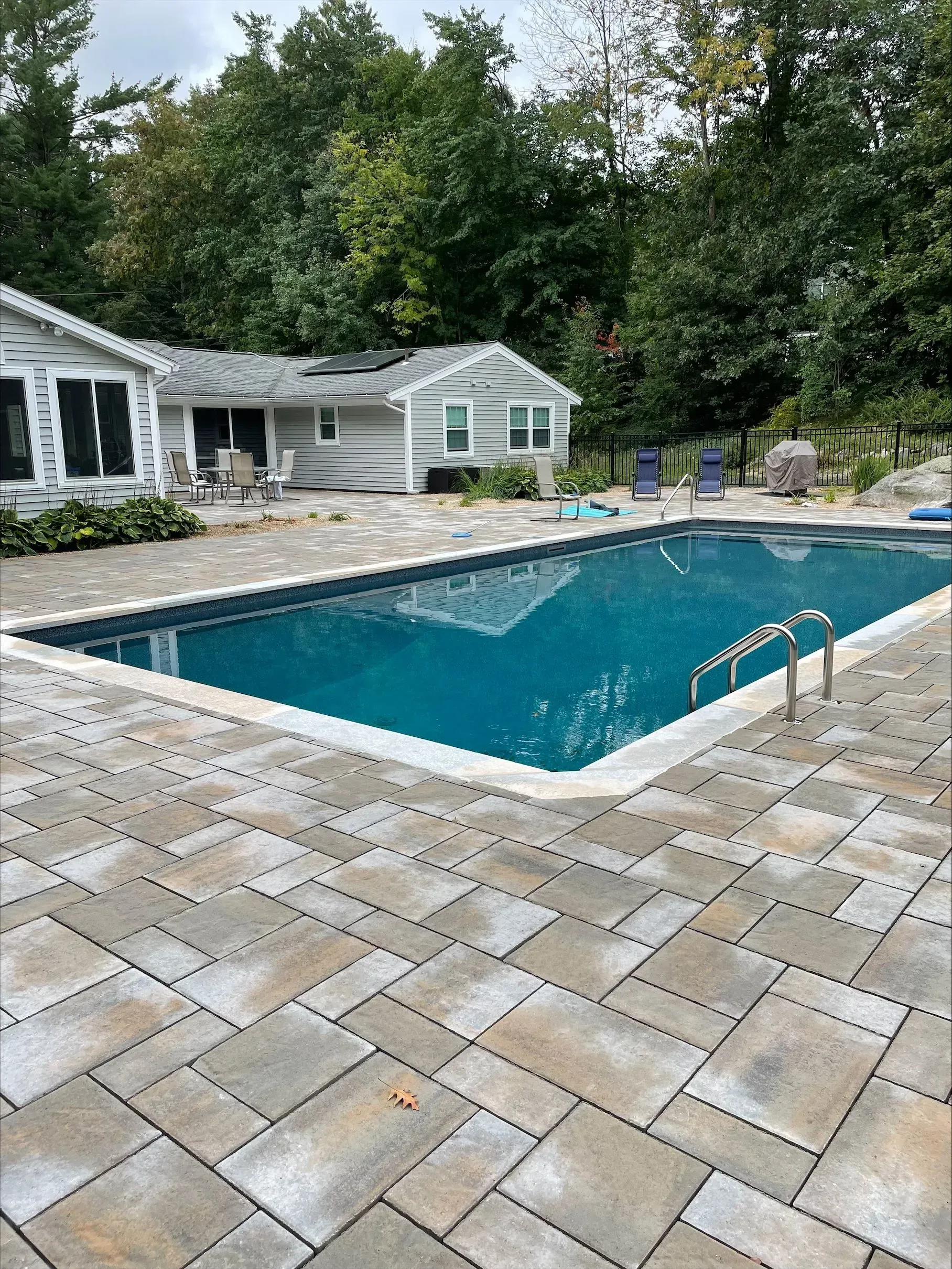 There is a large swimming pool in the backyard of a house.