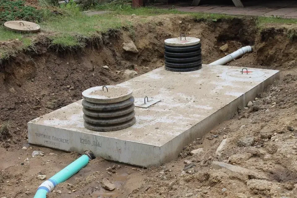 A concrete septic tank is being built in the dirt.