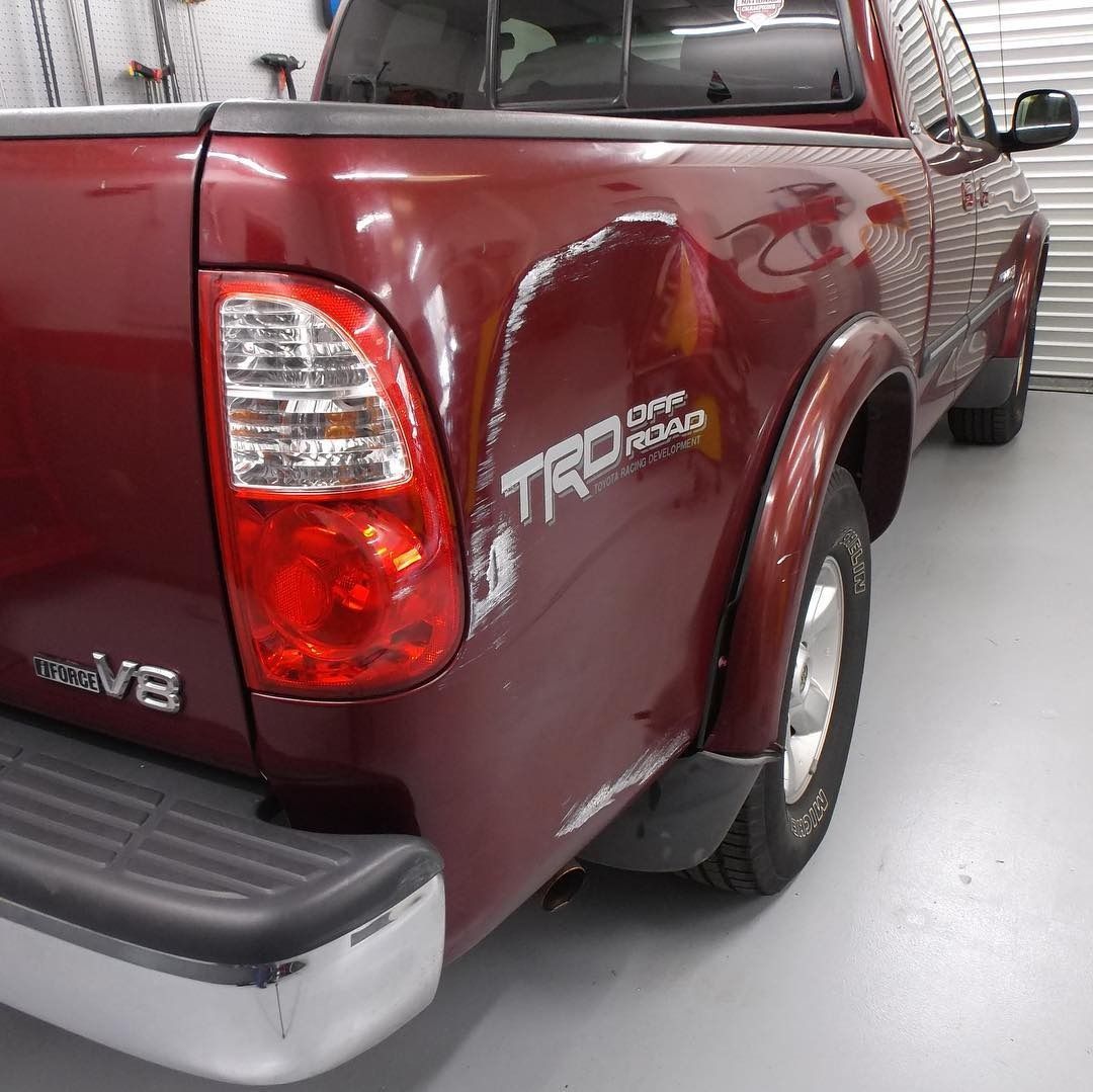 Red Toyota truck with rear quarter panel damage.