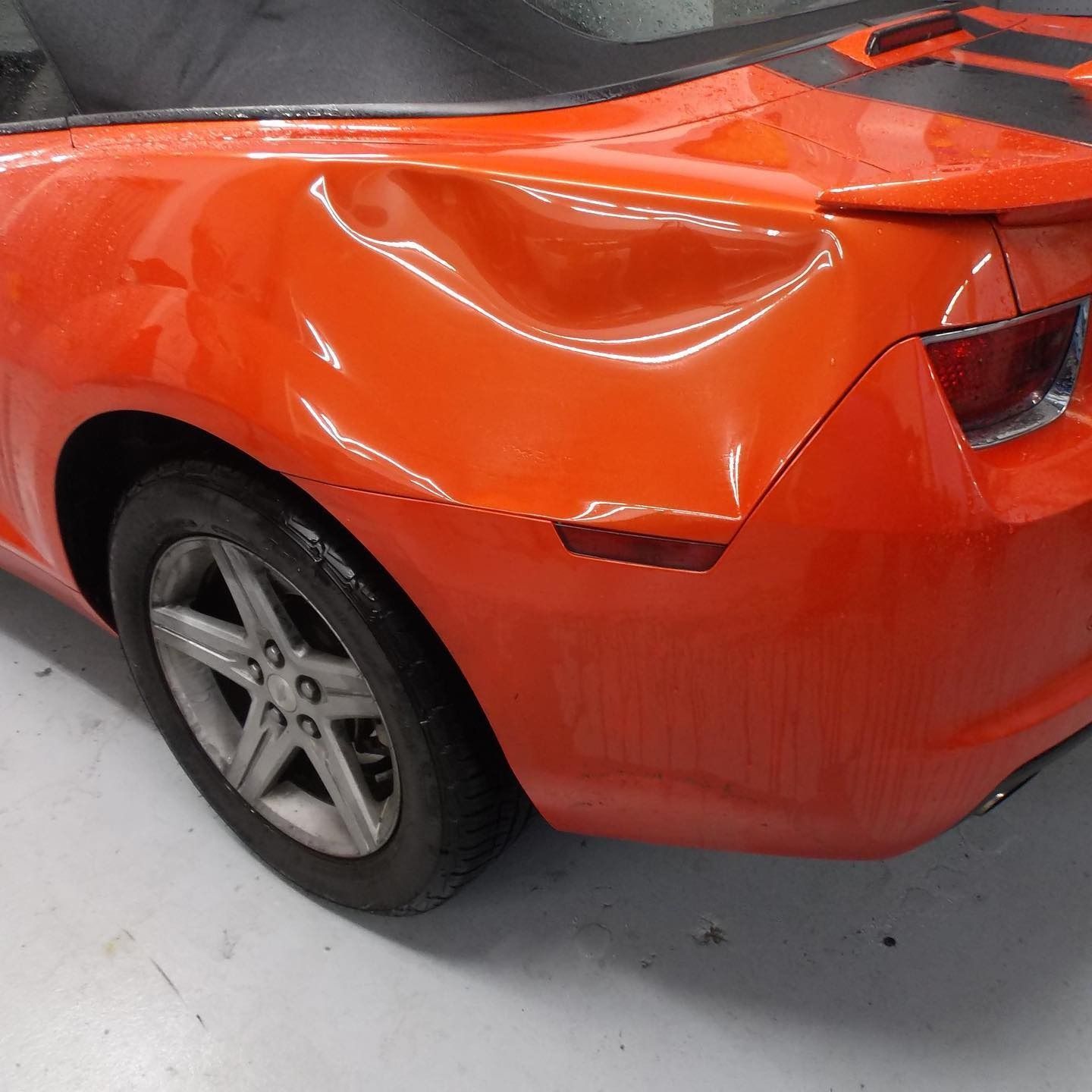Orange Camaro with a dent in the rear quarter panel.