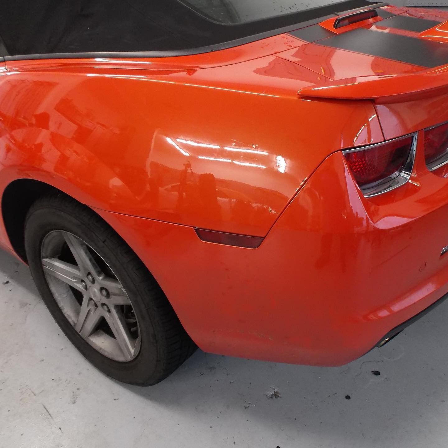 Orange Camaro convertible, rear quarter view, with black racing stripe.