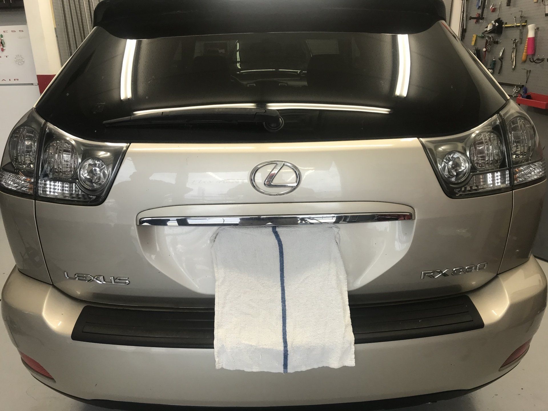 Back of a Lexus SUV with a white towel covering the license plate in a garage.