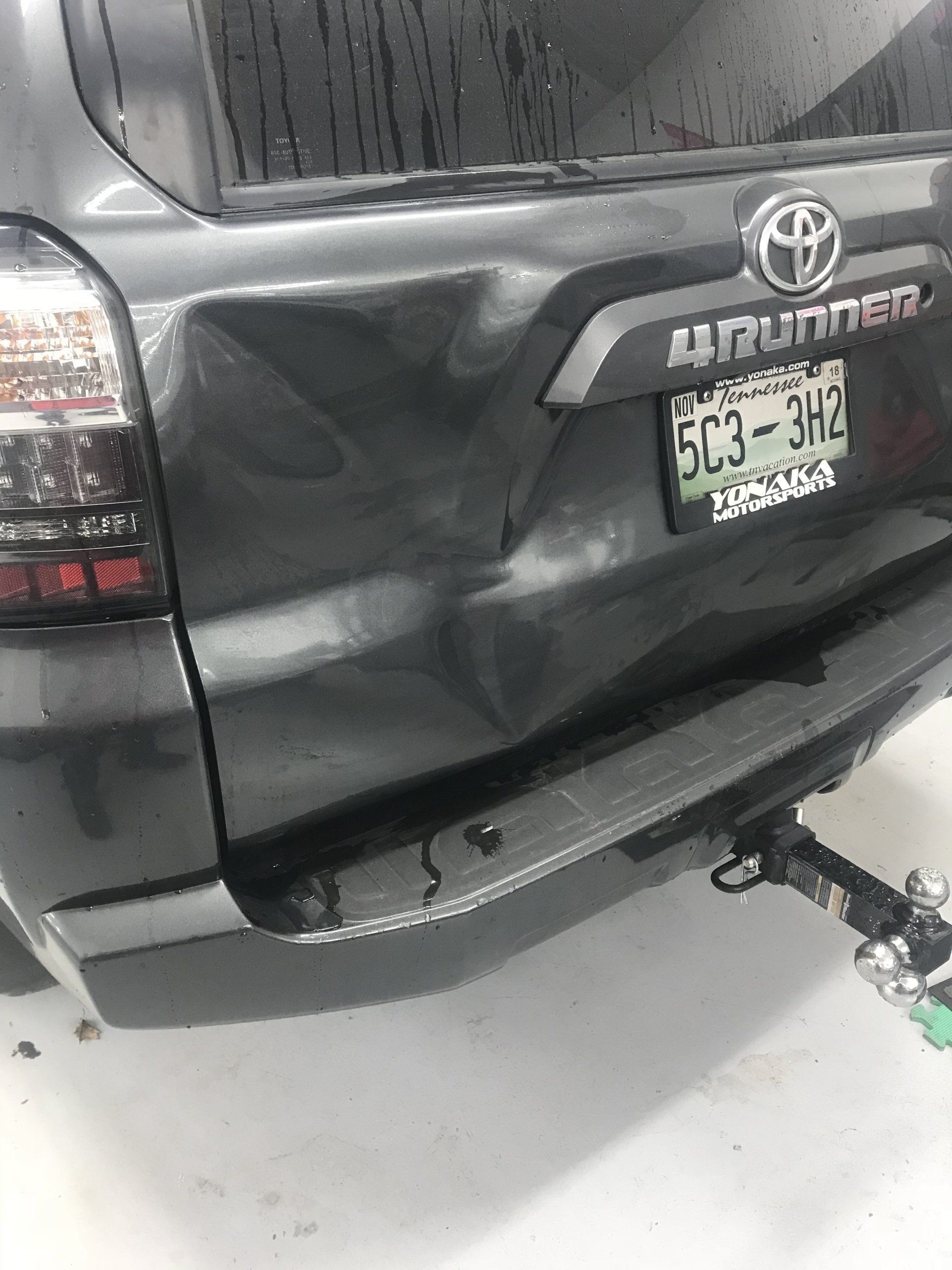 Dark gray Toyota 4Runner rear end with a large dent, damage from an accident.