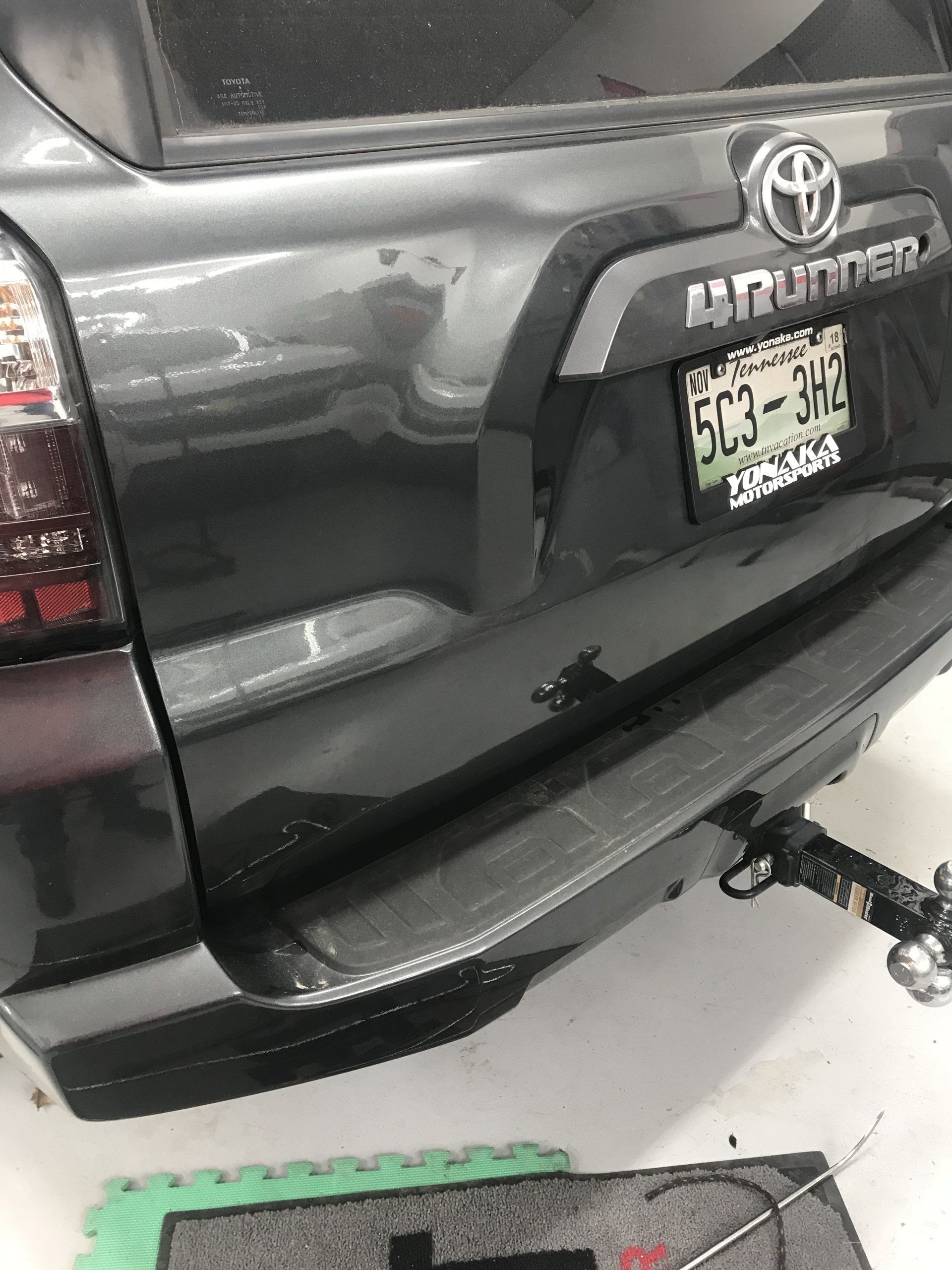 Gray Toyota 4Runner with a dented rear panel. The license plate reads 