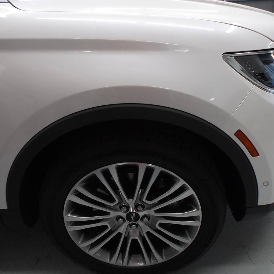 White car's front wheel and fender; black wheel well. Amber side marker light visible.