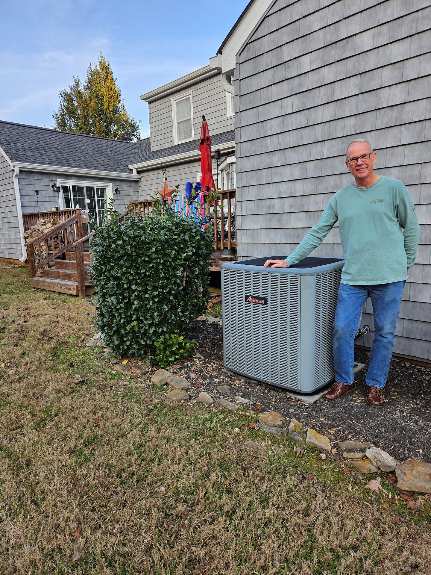 A man is standing next to an air conditioner outside of a house.