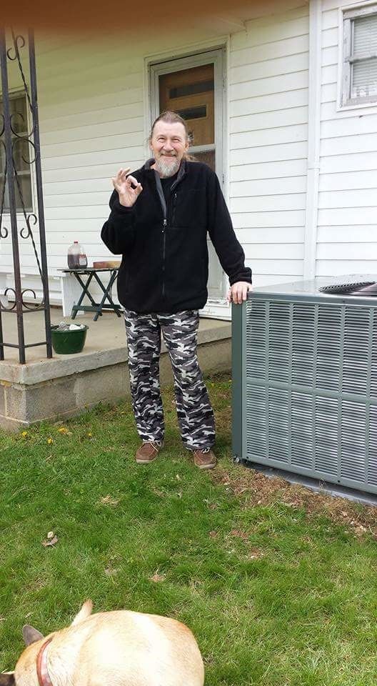 A man is standing in front of a house with a dog.
