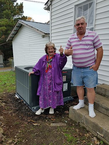 A man and a woman are standing next to each other in front of a house.