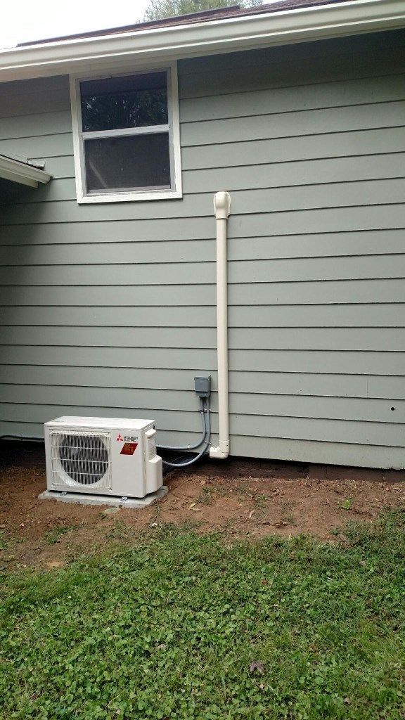A white air conditioner is installed on the side of a house.