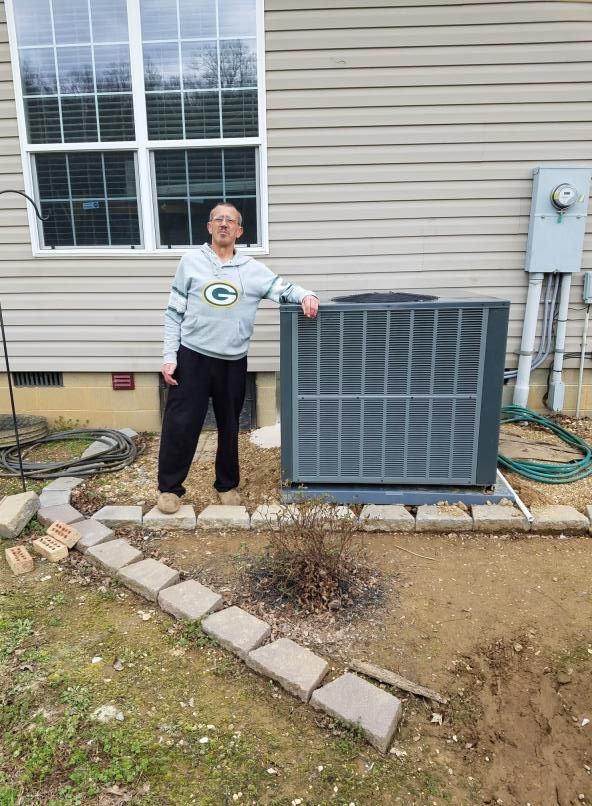 A man is standing next to an air conditioner in front of a house.