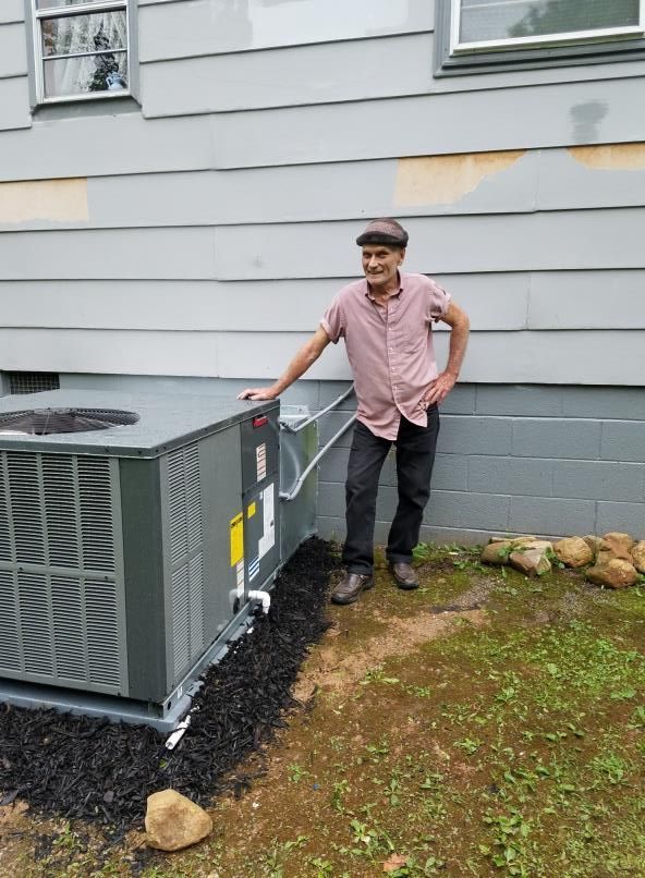 A man is standing next to a large air conditioner outside of a house.