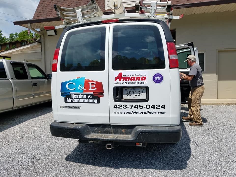 A white van is parked in front of a building with a man standing next to it.