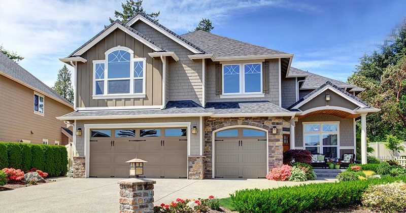 A large house with two garage doors and a large driveway.