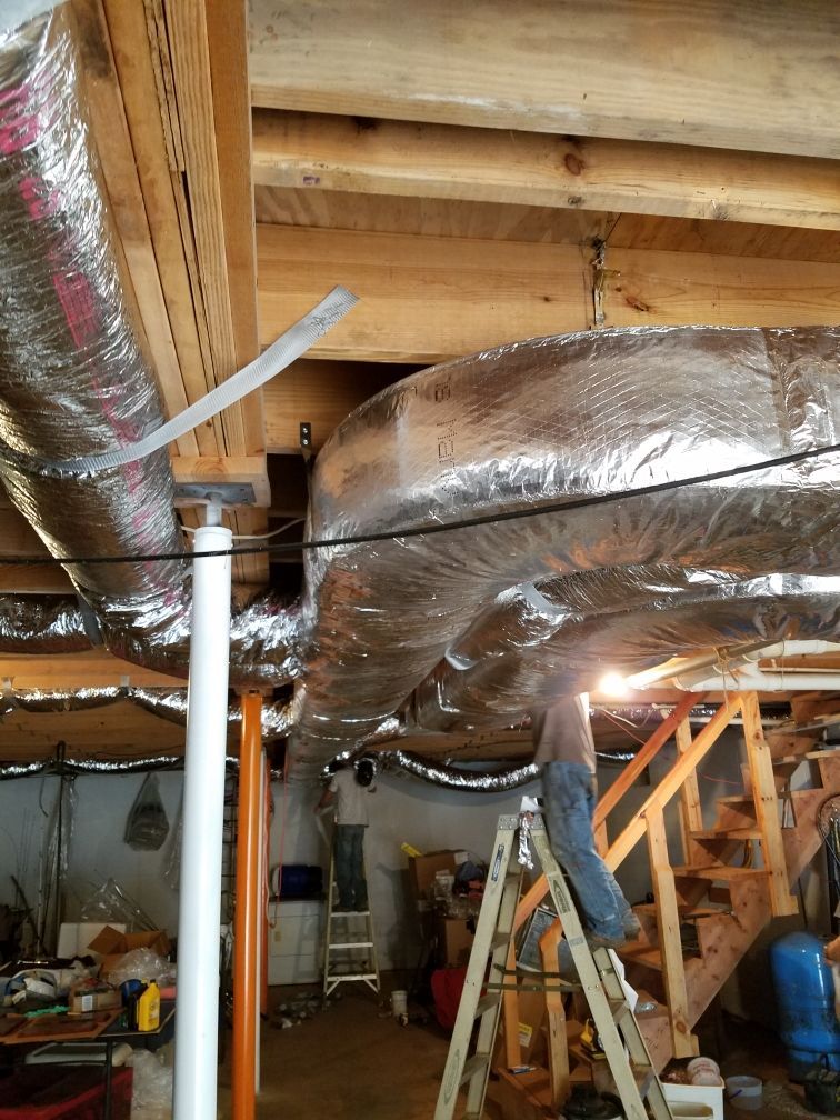 A man is standing on a ladder in a basement.