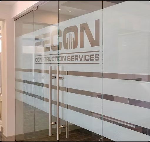Glass office doors with EECON Construction Services logo and frosted horizontal stripes