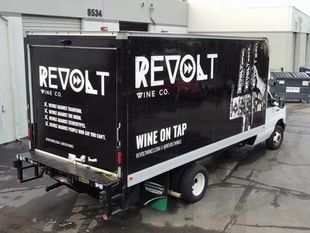 Black Revolt Wine Co. truck with “Wine on Tap” signage parked outdoors on a wet lot