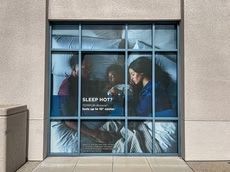 Window display with a sleeping woman and text reading “SLEEP HOT!”