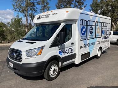 White commercial van with blue service logos parked on a road near trees
