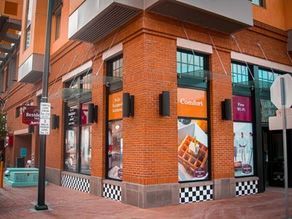 A brick-corner storefront with black-and-white checkered base and large windows on a city street