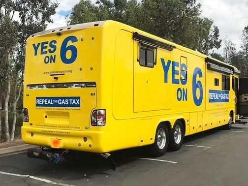 Yellow campaign bus with large blue “YES on 6” text parked in a lot