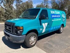 Turquoise utility van parked outdoors with bold white lettering on the side.