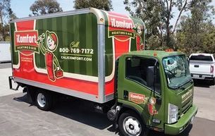 Green box truck with red-and-white moving company graphics parked on a street